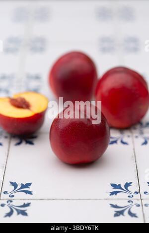 Shiny, ripe nectarines on white and blue tiles Stock Photo