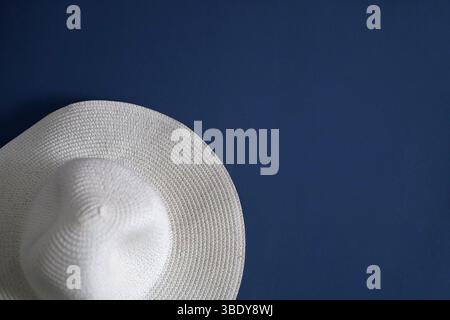 Elegant, white, braided hat hanging on the blue wall Stock Photo