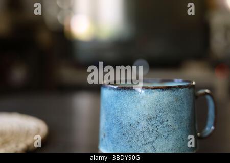 Beautiful handmade, turquoise ceramic mug on the dark wood table Stock Photo