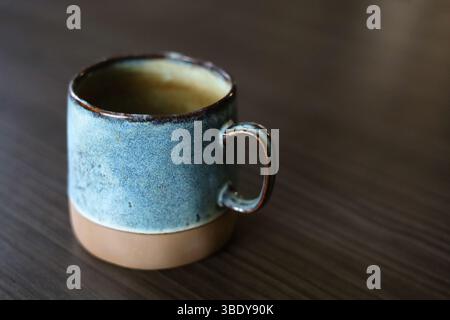 Beautiful handmade, turquoise ceramic mug on the dark wood table Stock Photo