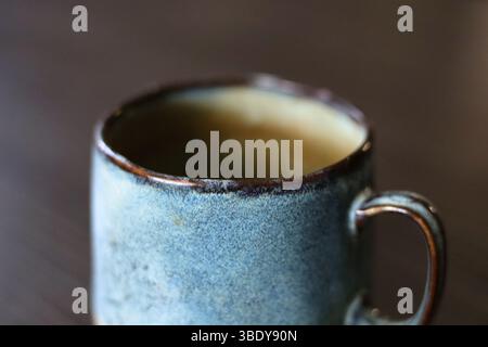 Beautiful handmade, turquoise ceramic mug on the dark wood table Stock Photo