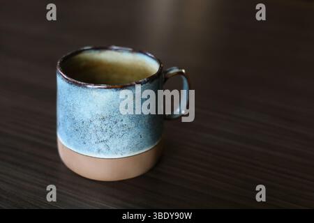 Beautiful handmade, turquoise ceramic mug on the dark wood table Stock Photo