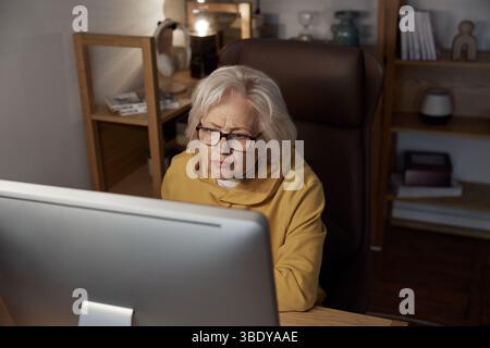 Focused elderly woman using desktop computer at home portrait shot Stock Photo
