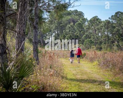 Couple with dog walking on trail in Scherer Thaxton Preserve in Venice Florida USA Stock Photo