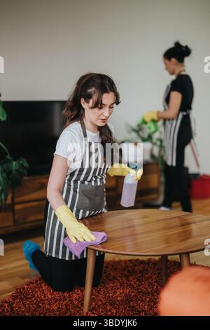 Two women engaged in cleaning work with gloves and aprons inside a ...