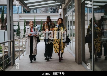 Three Diverse Young Professionals Collaborating Outdoors on a Business Campus Walkway Stock Photo