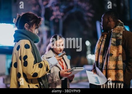 Group of multiracial colleagues collaborating outdoors during the evening in wintertime Stock Photo