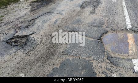 Dangerous potholes in the asphalt town road. Road damage, broken Stock Photo