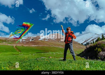 Boy hiker with kite on mountains background Stock Photo