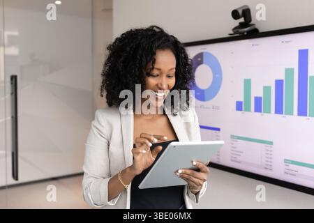 Smiling African woman using tablet in office Stock Photo