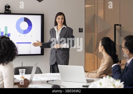 Young businesswoman confidently making presentation to colleagues in modern office Stock Photo