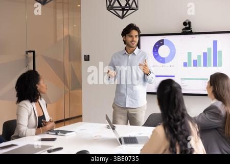 Young male professional presenting data to teammates Stock Photo