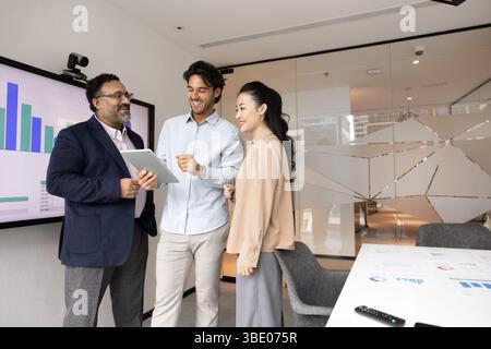 Three happy business professionals standing in boardroom with digital tablet Stock Photo