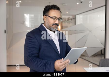 Indian analyst reviewing digital document or financial report on tablet Stock Photo