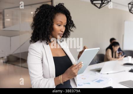 African businesslady using digital tablet device standing in meeting room Stock Photo