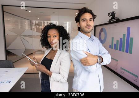 Two young teammates analysts posing for camera in meeting room Stock Photo