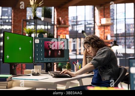 Focused woman using AI chatbot software and copy space display, turning text prompt into photos for a creative project. Young photographer uses text to image generative models on PC. Stock Photo
