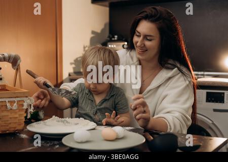 Gentle parenting moment in cozy kitchen as mom and toddler enjoy bonding over flour eggs and playful sensory experience full of laughter touch warmth Stock Photo