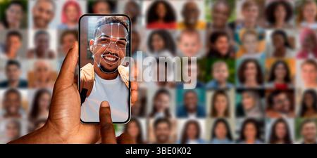 A hand holds a smartphone displaying a smiling person face Stock Photo