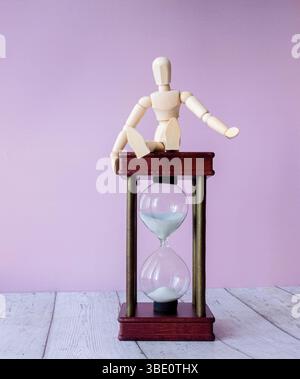 Close-up Of Hourglass In Front Of Businessperson's Hand Calculating Invoice Stock Photo