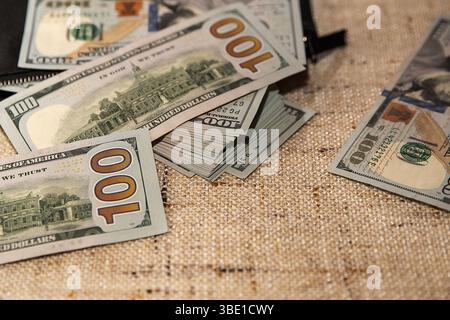 Stack of Hundred Dollar Bills Partially in a Black Wallet on a Table Stock Photo