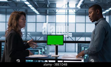 Data center team using mockup green screen tablet, reviewing paperwork files, and security protocols. Server room admins next to chroma key device analyzing critical system reports, camera A Stock Photo