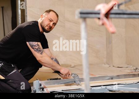 Construction worker cutting ceramic tile using tile cutter while working on bathroom renovation Stock Photo