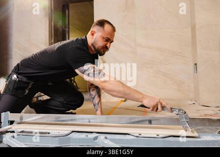 Construction worker cutting ceramic tile using tile cutter while working on bathroom renovation Stock Photo