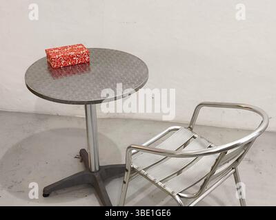 A gift box on a round table with empty chairs in a room Stock Photo
