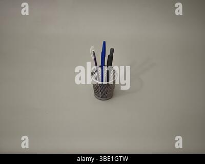 Pencils and pens in a container on a grey background Stock Photo