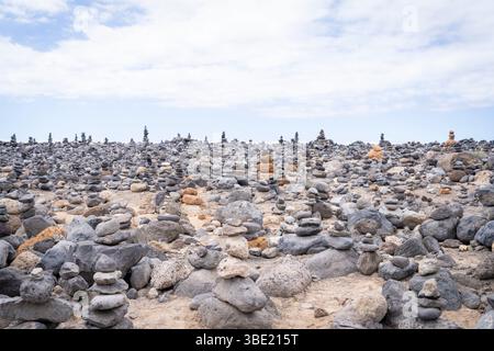 Cairns by the sea, Costa Adeje, Tenerife. Piles of stones balanced on a beach in Costa Adeje. Art of stone balance or rock stones piles at Beach. Stock Photo