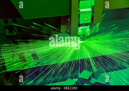 CNC laser cutting metal sheet with bright sparkle in factory. Stock Photo