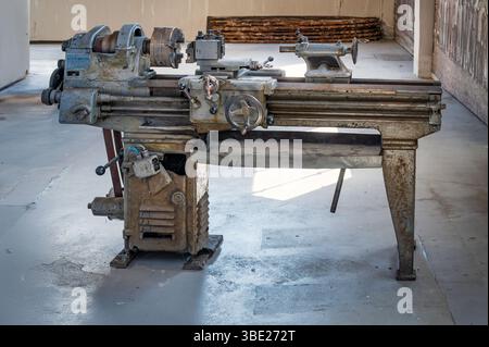 Old lathe machine stands in a workshop, a testament to past manufacturing processes Stock Photo