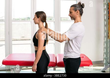 Physiotherapist examining posture of female patient in clinic Stock Photo