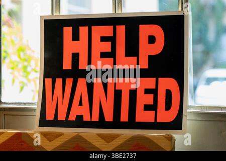 Help wanted sign displayed in window, advertising job opportunities and seeking applications Stock Photo