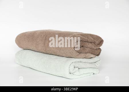 Light blue and brown towels, rolled up on white background, hygiene and home textile item Stock Photo