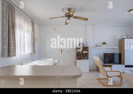 A kitchen breakfast bar with view into a modern living space, blending function and comfort in a naturally lit interior. Stock Photo