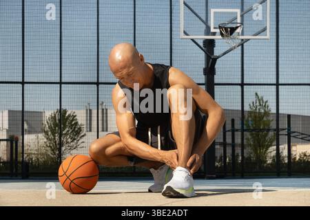 Basketball ankle injury or pain. Professional athlete or sportsman with accident. Man check pain in leg after sport workout. Stock Photo