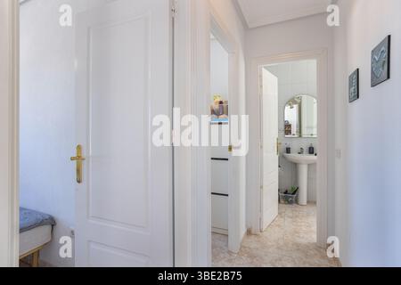 A compact bedroom with two single beds and a large built-in white wardrobe, designed in a minimalist style with soft tones. Stock Photo