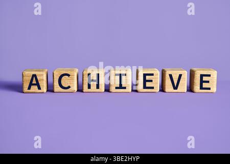 Achieve word on wooden cubes blocks over purple background. Motivation concept Stock Photo