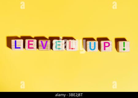 Colorful Level Up text on wooden blocks over bright yellow background. inspiration concept Stock Photo
