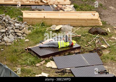 Construction worker resting on timber during break at a chaotic building site as quiet moment amid the hustle of urban development in Sofia Bulgaria Stock Photo