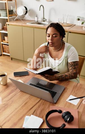 Focused young woman works on her laptop while taking notes at her comfortable home desk. Stock Photo