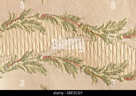 detail of the embroidery of a brocade fabric with a yellow floral motif in relief on a beige base. Intricate vines and floral motifs in soft tones wea Stock Photo