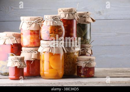Many jars with different pickled products on wooden table Stock Photo