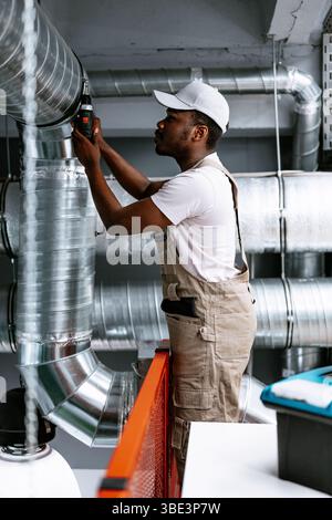 Professional worker repairing ventilation system in commercial building during daytime Stock Photo