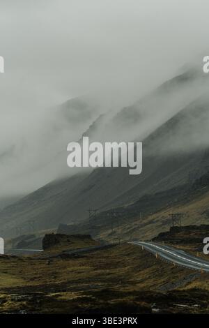 Moody view of road number 1 winding through foggy East Iceland hills. Stock Photo