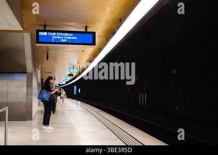 23-05-2025 Zurich, Switzerland. Passengers on an underground platform waiting for the train. Wide angle view, ceiling mounted lights, illuminated trai Stock Photo