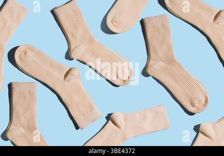 Pattern of cream-colored ribbed socks on light blue background. Concept of socks texture and design for fashion and textile applications. Stock Photo