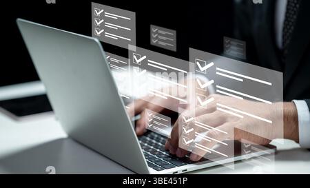 Businessman using a laptop while showing a questionnaire with a checkmark icon. Tablet on the table. Technology innovation on a virtual screen. Concep Stock Photo